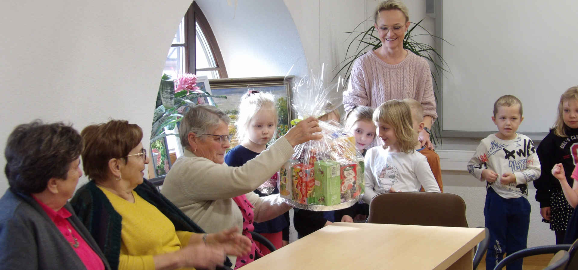 Dzieci wręczają prezent dla seniorów