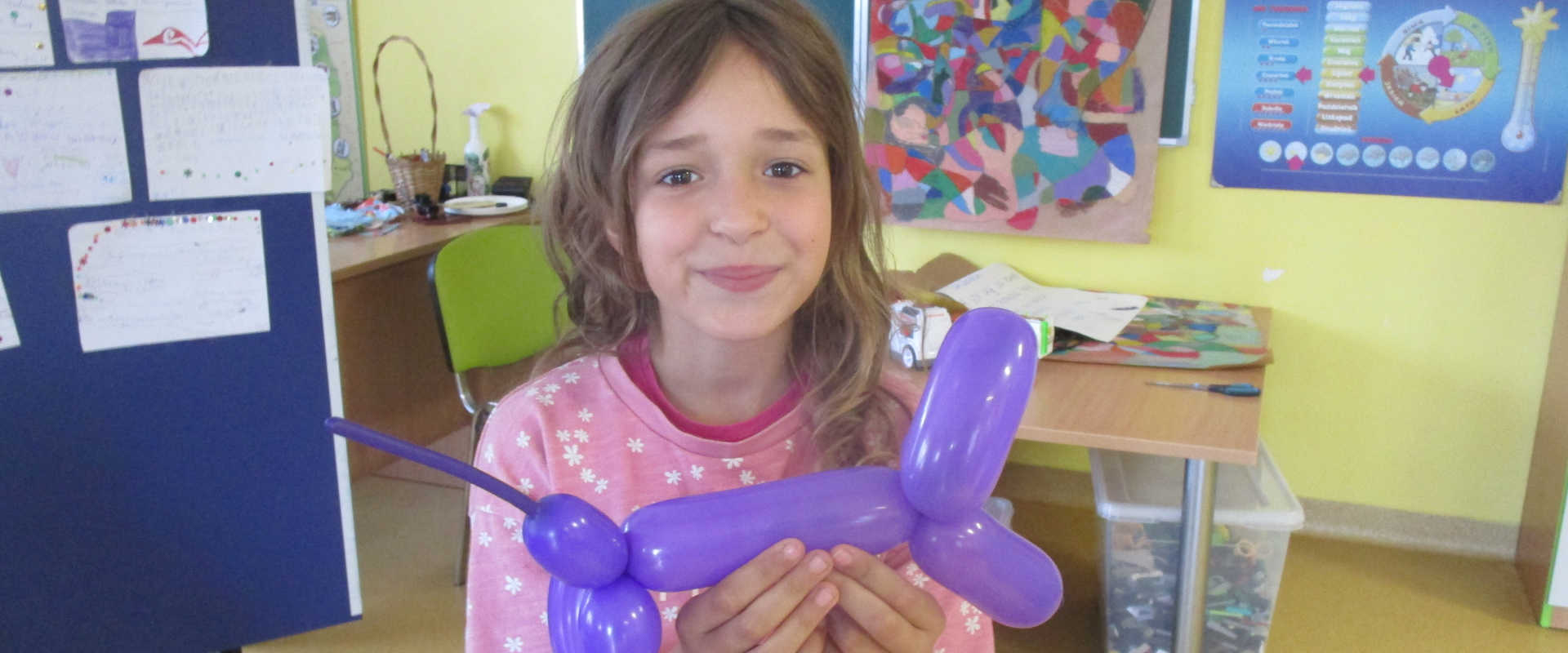 Dziewczynka z pieskiem zrobionym z fioletowego balonu