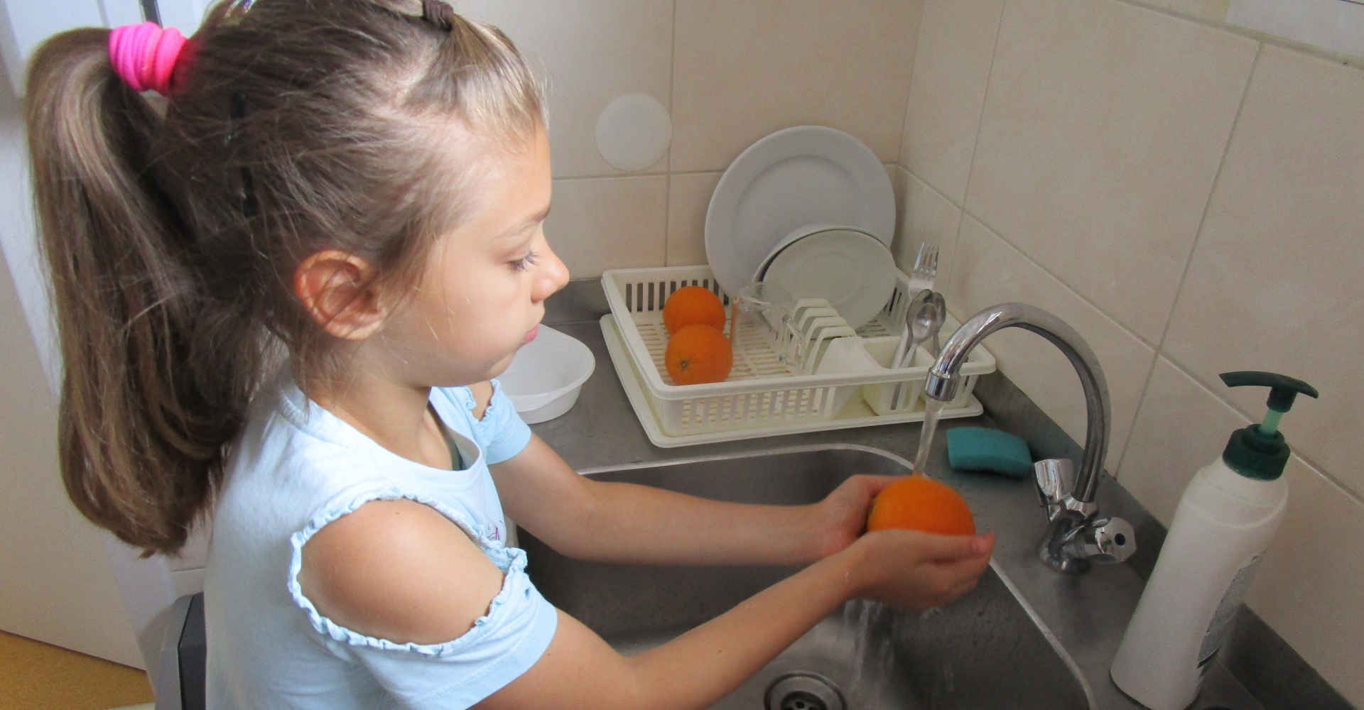 Dziewczynka myje pomarańcze